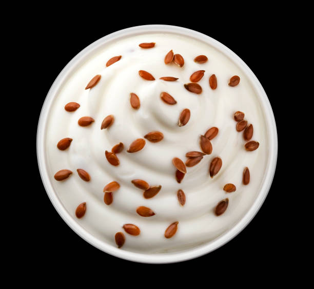 Bowl of yogurt with flax seeds isolated on black background, top view