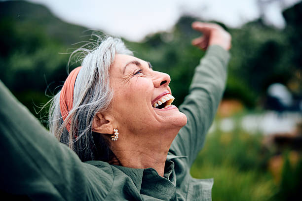 Carefree woman in her 60s with arms outstretched, fresh air, vitality, freedom