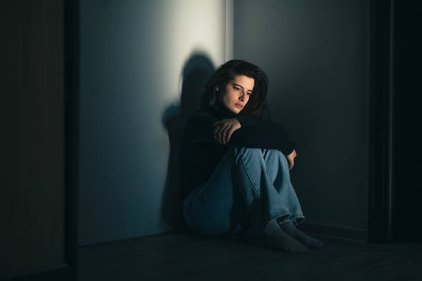 Shot of a sad and lonely woman at home sitting on the floor and contemplating.